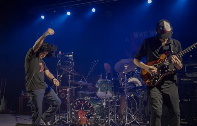 Vocalist, drummer, and guitarist performing onstage