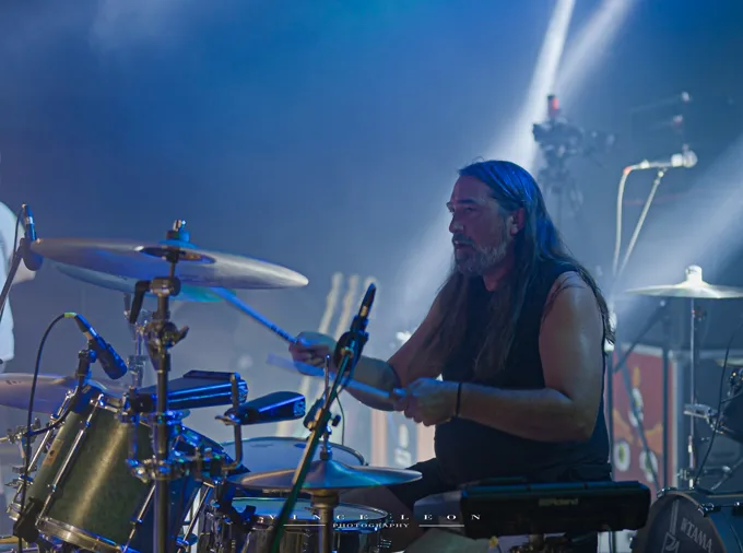 Drummer playing under blue stage lights