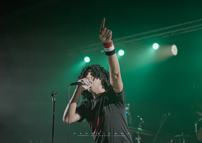 Vocalist raising a hand under green lights