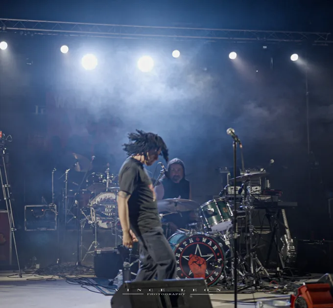 Vocalist crossing the stage in front of the drums